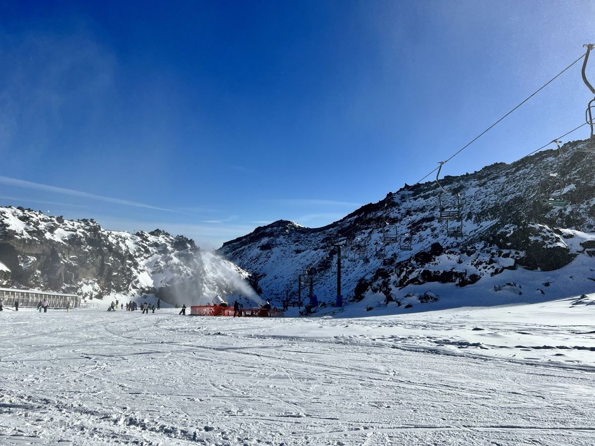 a snow covered mountain with a ski lift in the background.
